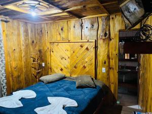 1 dormitorio con cama azul y pared de madera en Altos da Serra, en São José dos Ausentes