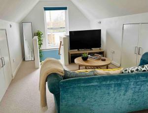 a living room with a blue couch and a tv at The Hideaway: Farnsfield (5 mins from Southwell) in Farnsfield