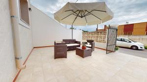d'une terrasse avec un canapé et un parasol sur un balcon. dans l'établissement Aura Salenta - A 400m dal mare, à San Pietro in Bevagna