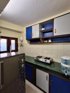 a kitchen with blue cabinets and a black refrigerator at Anand Niketan Homestay Shimla in Shimla