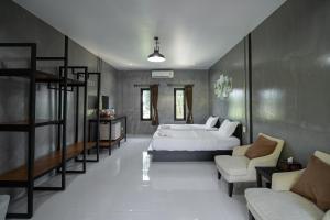 a bedroom with a bed and a couch and chairs at The Loft Panwa Resort in Panwa Beach