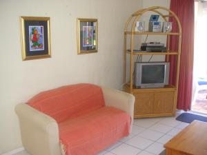 a living room with a chair and a tv at Waterside Living CL16 in Jeffreys Bay