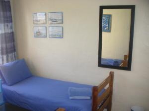 a bedroom with a blue bed and a mirror at Waterside Living CL16 in Jeffreys Bay