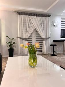 a vase with flowers on a table in a living room at Apartament Zamojski Młyńska in Zamość