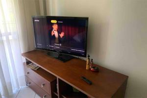 Une télévision à écran plat est installée au-dessus d'une table en bois. dans l'établissement Hochheim Beachside Itapema, à Itapema