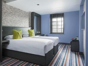 a bedroom with a white bed and white walls at Village Hotel Glasgow in Glasgow