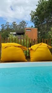 - deux oreillers jaunes assis à côté de la piscine dans l'établissement Nidos de carnota, à San Mamede de Carnota