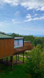 una casa con una terraza de madera en un campo en Nidos de carnota, en San Mamede de Carnota