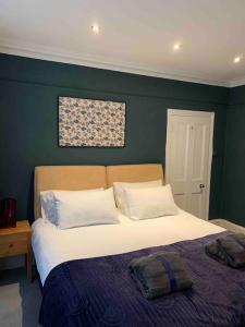 a bed in a bedroom with a green wall at London 2 Bedrooms with Private Garden Apartment Walking Distance to Underground Ideal for Families in London