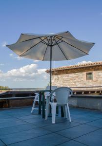 einen Tisch und Stühle mit Sonnenschirm auf einer Terrasse in der Unterkunft Locanda della Rocca in Sarnano