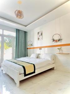 une chambre avec un grand lit blanc dans une pièce dans l'établissement HY GUESTHOUSE PHU QUOC - Nhà Hy vivu bên Vườn, à Duong Dong