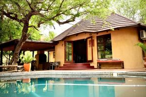 a house with a swimming pool in front of it at Hyenas Call in Marloth Park
