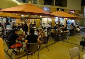 personas sentadas en mesas en un restaurante bajo sombrillas en Vacation Family Dept 2 Via Costa American Consulate, en Guayaquil