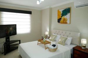 Sala de estar con cama blanca y TV en Vacation Family Dept 2 Via Costa American Consulate, en Guayaquil