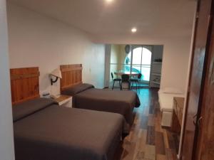 Habitación de hotel con 2 camas y mesa en Hotelito Escondido en Manzanillo