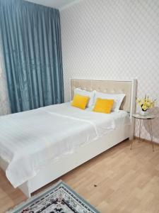Квартиры Уют в Туркестане في Türkistan: سرير أبيض مع وسادتين صفراء في الغرفة