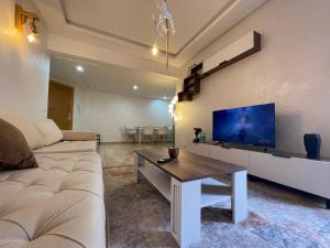 uma sala de estar com um sofá e uma televisão em Cosy & spacious apartment em Temara