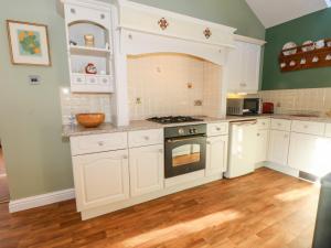 cocina con armarios blancos y horno en Molls Cottage, en Nantwich