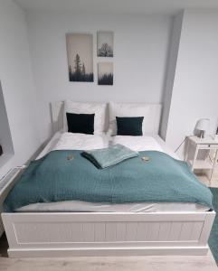 a white bed with a green blanket and two pillows at Ferienwohnung am See in Harsum
