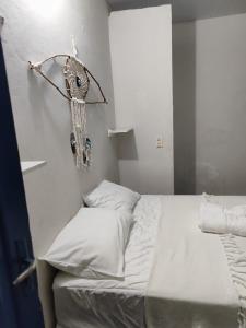 a bed with white sheets and pillows in a room at Hospedaria Arte Sagrada in Canguaretama