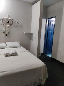 a bedroom with a white bed with a blue door at Hospedaria Arte Sagrada in Canguaretama