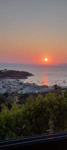 a sunset over a city with the ocean and a town at MENTA APT in Agia Pelagia