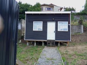 una casa grande y negra con una escalera en un patio en Cabaña Balmaceda - Puerto Montt, en Puerto Montt