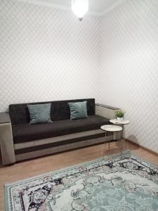 Квартиры Уют в Туркестане في Türkistan: أريكة في غرفة مع سجادة وطاولة
