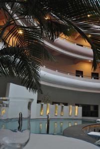 a building with a pool and a palm tree at The Hans Hotel in Hubli