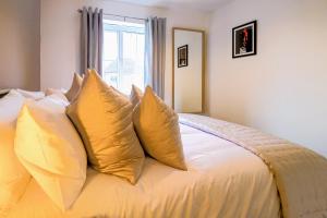 uma cama com almofadas amarelas com uma janela em Charming 3 Bedroom, 2 Bathroom Home in Northampton - SKY TV included, Free Parking & WiFi by HP Accommodation em Northampton