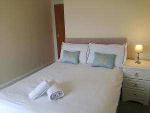 uma cama branca com duas toalhas enroladas em Harbourside 2 em Dartmouth