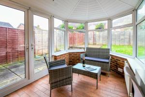 a conservatory with a table and chairs and windows at Charming 3 Bedroom, 2 Bathroom Home in Northampton - SKY TV included, Free Parking & WiFi by HP Accommodation in Northampton