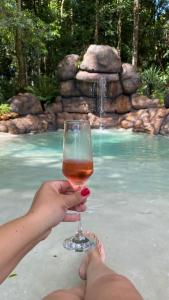 a person holding a glass of wine in front of a swimming pool at Econtainer Suítes Macacos in Macacos