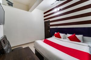 60800 Hotel Landlord في Rohtak: غرفة نوم بسرير ومخدات حمراء وجدار مخطط