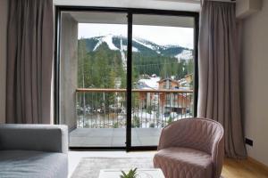 a living room with a large window with a mountain view at DAMIAN JASNA HOTEL RESORT and RESIDENCES in Demanovska Dolina
