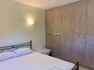 1 dormitorio con cama blanca y armarios de madera en Sea melodies apartment 2, en Koroni