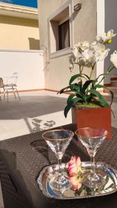 - une table avec 2 verres à vin et des fleurs dans l'établissement Aura Salenta - A 400m dal mare, à San Pietro in Bevagna