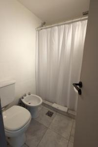 baño con aseo y cortina de ducha blanca en M382 Hotel Bariloche en San Carlos de Bariloche
