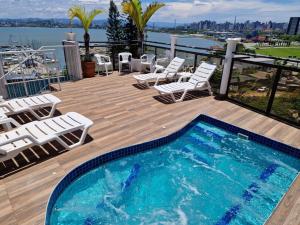 a deck with chairs and a swimming pool on a balcony at HOTEL DAIFA in Florianópolis