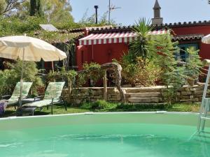 a swimming pool with an umbrella and chairs and a house at Eco Moyano Posada in Gaucín