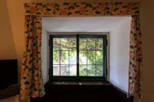 - une fenêtre dans une chambre avec un rideau dans l'établissement Castello e Borgo di Porciano, à Pratovecchio