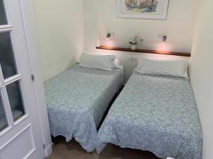 2 camas en una habitación pequeña con ventana en Apartamento La Vasca, en El Puerto de Santa María