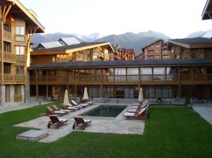a resort with a pool and chairs and a building at Stylish wooden apartment with terrace in Pirin Golf Hotel&Spa Complex in Razlog