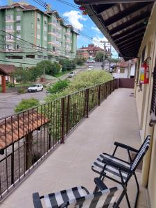 a balcony with chairs and a view of a street at Apartamento no centro in Canela