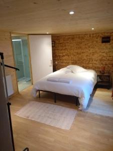a bedroom with a white bed and a brick wall at La Maison Bleue in La Cabanasse