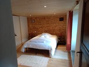 1 dormitorio con 1 cama con sábanas y almohadas blancas en La Maison Bleue, en La Cabanasse