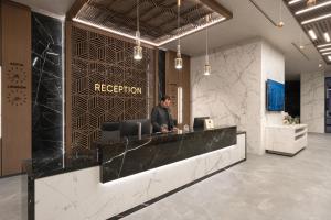 a man sitting at a reception desk in a lobby at Atmosphere Balneo Hotel & SPA in Pavel Banya