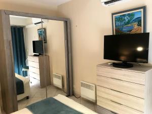 een woonkamer met een televisie op een dressoir met een spiegel bij Appartement d'une chambre avec vue sur la mer balcon et wifi a Frejus in Fréjus
