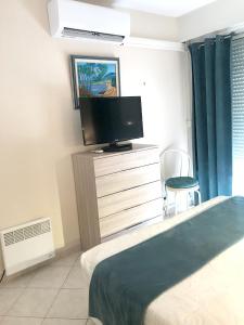 een slaapkamer met een bed en een tv op een dressoir bij Appartement d'une chambre avec vue sur la mer balcon et wifi a Frejus in Fréjus