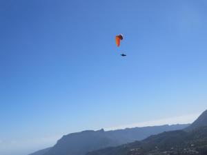 un parapente volando en el cielo sobre las montañas en Finca Cortez Apartment 4 en San Bartolomé